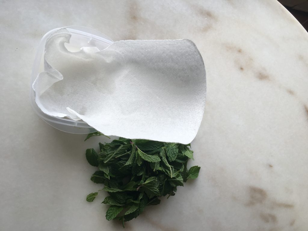 kitchen towel inside storage container with herbs aside